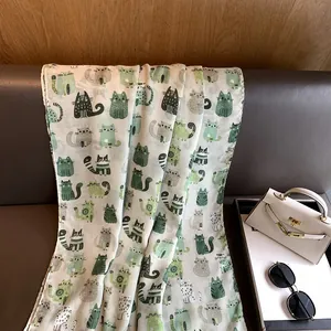 Detail shot of lightweight cotton linen scarf featuring green cartoon cat patterns