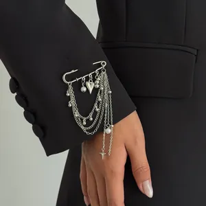 Detail of silver safety pin brooch with layered chains and star charms on black blazer