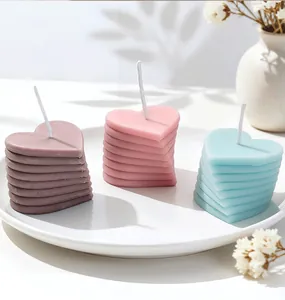 Détail de bougies parfumées empilées en forme de cœur en violet, rose et bleu clair