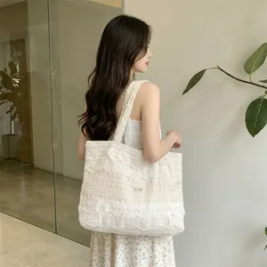 Detailed close-up of white crochet lace tote bag with delicate ruffle trim and brand label