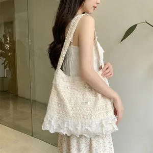 Detailed close-up of ivory crochet lace shoulder bag with ruffled trim and brand tag