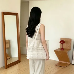 Detail of white lace crochet tote bag with intricate floral patterns for summer beach