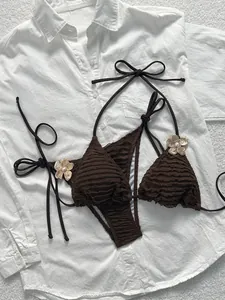 Detailed view of brown textured bikini with gold flower accents and pearl center