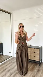 Detail of brown pinstripe vest and wide-leg trousers set in cozy home interior