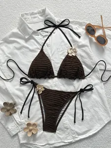Detailed flat lay of dark brown bikini with golden flower and pearl accents