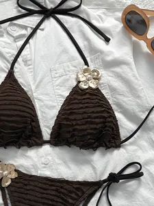 Close-up of brown bikini fabric with frill texture and gold floral pearl accents