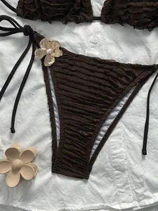Detail of dark brown bikini with pleated texture and gold metal flower with pearl