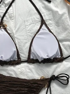 Flat lay of brown textured bikini set with golden Medusa logo hardware detail