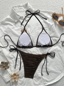 Flat lay of brown two-piece bikini with gold buckles and chic vacation accessories