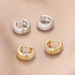 Nahaufnahme von goldenen und silbernen Huggie-Ohrringen mit Zirkonia und hohlen Details