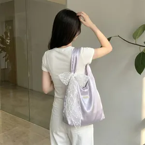 Detail of purple satin tote bag featuring a white lace bow and silky texture finish