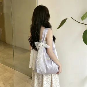 Detailed view of lilac satin tote bag with large white lace bow and shoulder strap