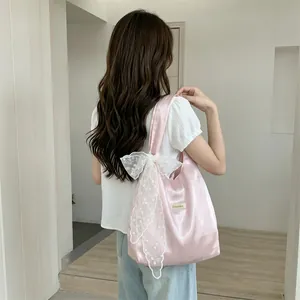 Detail of pink satin tote bag featuring large white lace bow and Sezakka brand label