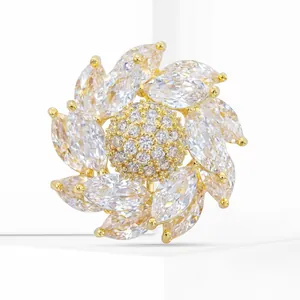 Détail macro d'une broche fleur rotative avec zircons marquise et monture dorée