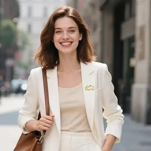 Broche géométrique évidée en métal doré sur le revers d'un blazer blanc chic