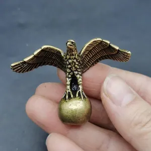 Macro shot of a vintage brass eagle figurine clutching a sphere with antique metal finish