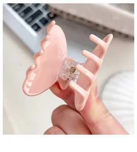 Détail de la pince à cheveux papillon en acétate rose à fleurs avec ressort solide