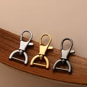 Close-up of swivel lobster clasps in silver, gold, and gunmetal on a wooden surface