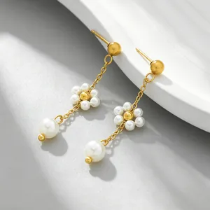 Close-up of elegant gold dangle earrings with white pearl flower and chain details