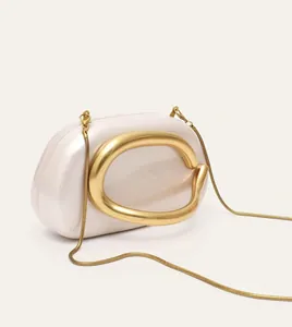 Minimalist creamy white shell acrylic clutch bag with a sculptural gold metal ring handle