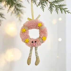 Close-up of pink plush Christmas wreath with gold stars and striped legs on pine branch