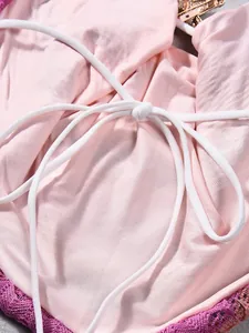 Detail of pink crop top with white tie-up straps and purple crochet lace trim finish