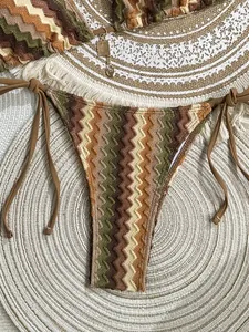 Detail of striped crochet bikini bottom with side ties and gold palm tree charm