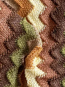 Macro view of textured chevron knit fabric with earthy brown, orange and green stripes