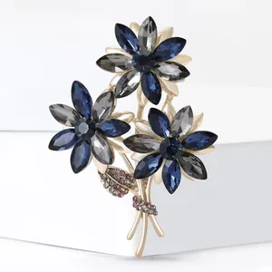 Detail shot of elegant bouquet brooch with grey and blue crystals on golden alloy