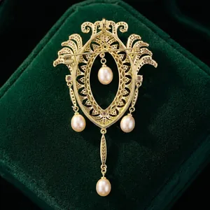 Broche vintage dorée aux motifs évidés élégants et quatre perles sur velours vert