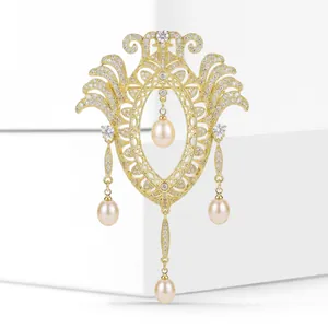 Gros plan d'une broche vintage dorée avec micro-pavé de zircons et perles pendantes