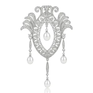Broche vintage en argent avec cristaux pavés et perles en goutte sur fond blanc