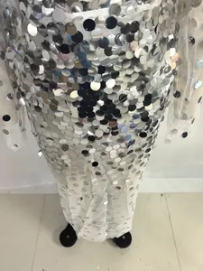 Detail of silver mirror sequins on white mesh fabric for a sexy evening gown