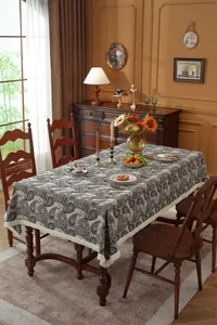 Detail of vintage paisley floral tablecloth with cream tassels on a wooden table