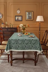 Close-up of vintage dark green paisley jacquard tablecloth with beige fringe tassels