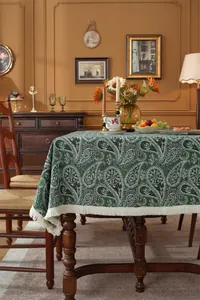 Detail of vintage paisley dark green jacquard tablecloth with elegant cream fringe edges