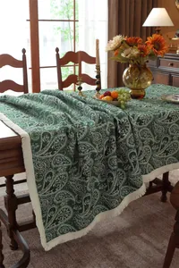 Macro detail of dark green paisley jacquard tablecloth with elegant white tassels