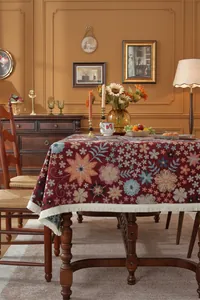 Detail of vintage floral jacquard tablecloth with beige tassels in a warm room setting