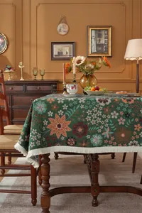 Close-up of vintage dark green floral jacquard tablecloth with elegant white tassels