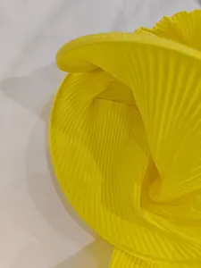 Détail du tissu plissé jaune vif montrant des plis fins et un fini satiné brillant