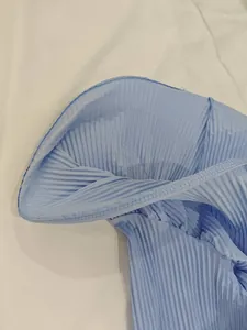 Vue détaillée du tissu plissé bleu clair avec coutures fines sur le bord