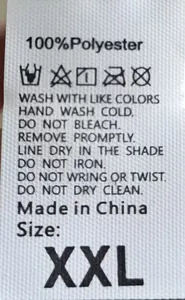 Detail of clothing care label showing 100% polyester fabric and washing instructions