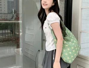 Casual lifestyle view of a green floral canvas tote bag with yellow flower prints