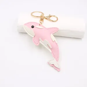 Detailed view of pink and white faux leather dolphin keychain with gold metal ring