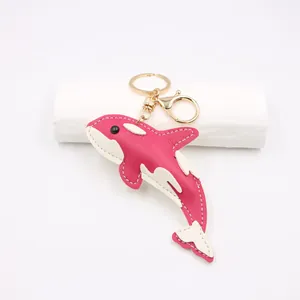 Detail of pink faux leather orca keychain with white stitching and gold lobster clasp