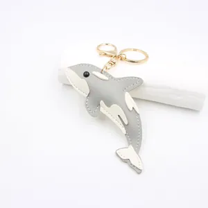 Detail showing high-quality gray PU leather whale keychain with white stitching
