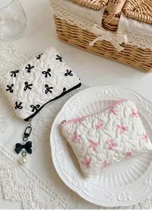 Detail of quilted cosmetic bag with ribbon patterns and pearl bow zipper pendant