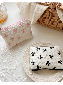 Detailed heart-quilted makeup bags featuring pink and black bow prints in a cozy setting