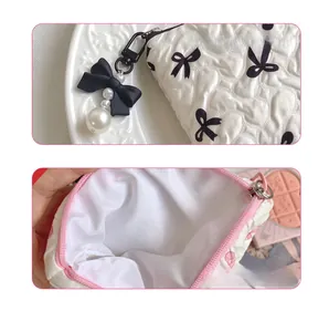 Close-up of quilted cosmetic bag with black bow patterns and pearl charm accessory