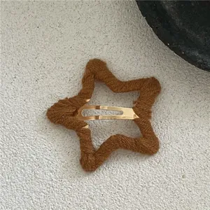 Close-up of brown plush yarn-wrapped star hair clip with golden metal snap fastener